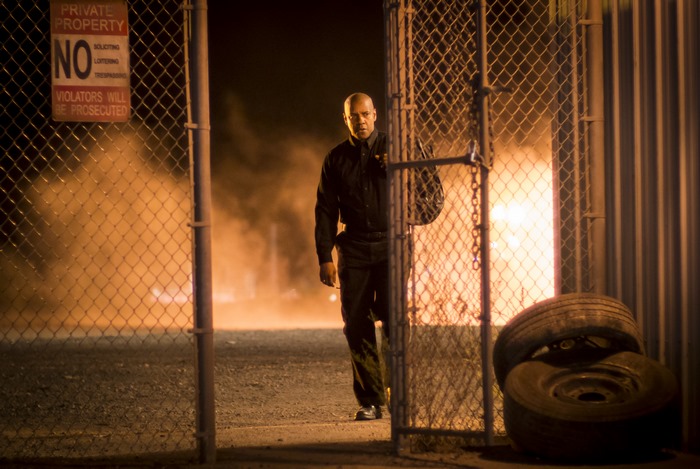 Denzel Washington walks through a gate at night