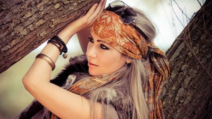 Woman with headscarf leaning on tree