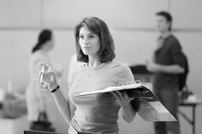 Gemma Arterton holding a glass of water and a binder