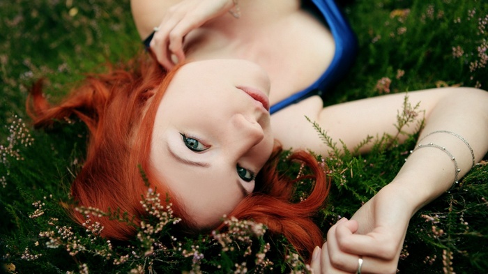 Woman with red hair lying in grass