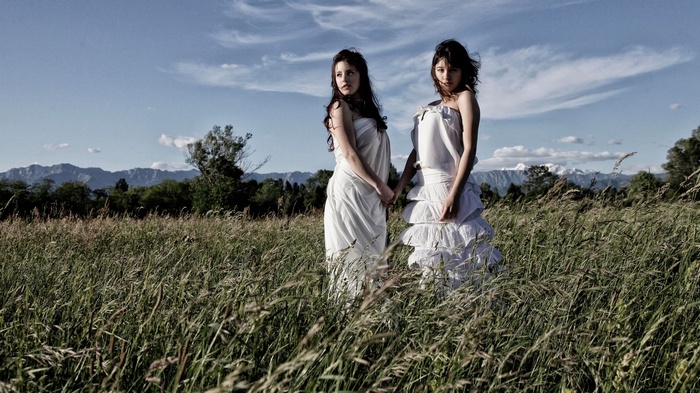 Two women in white dresses in a field
