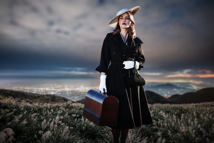 Kate Winslet in vintage attire holding a suitcase