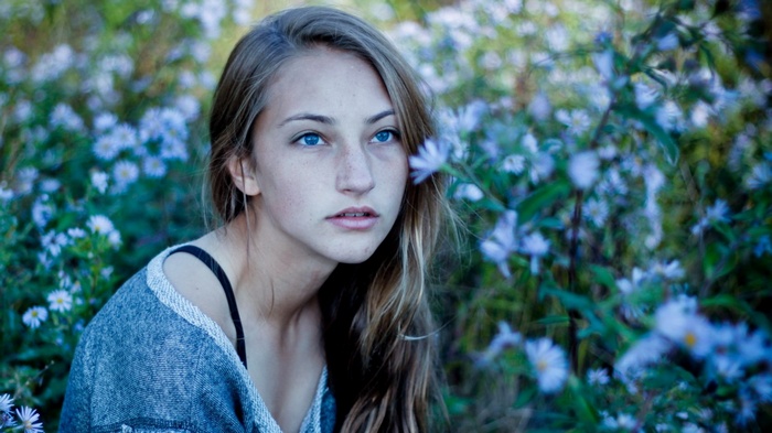 Young woman with blue eyes in a field of flowers