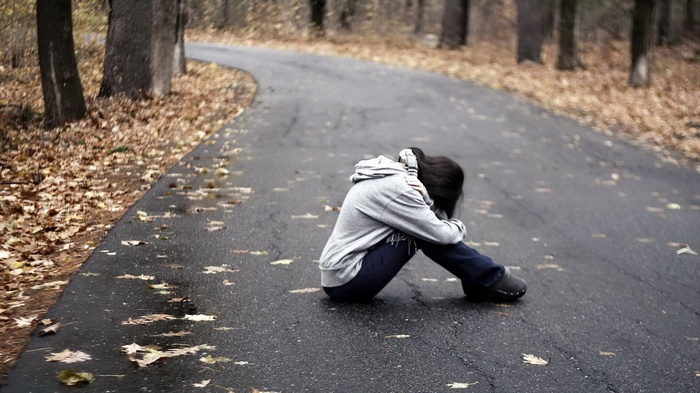 Person sitting on a road in autumn
