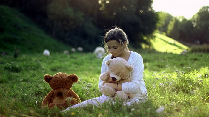 Girl with teddy bears in a grassy field
