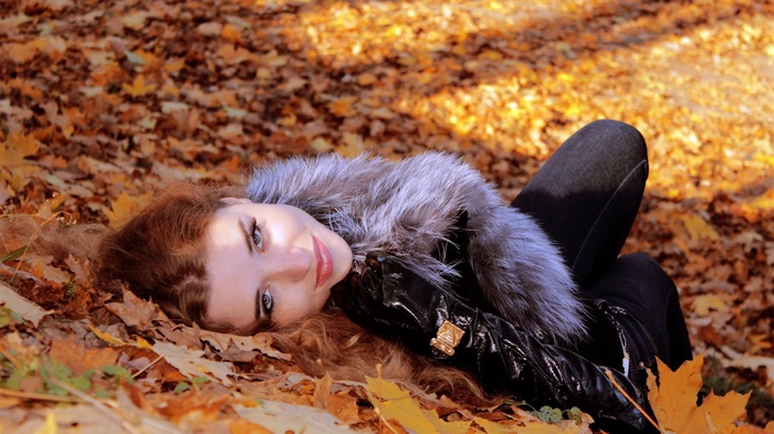 Woman lying in autumn leaves