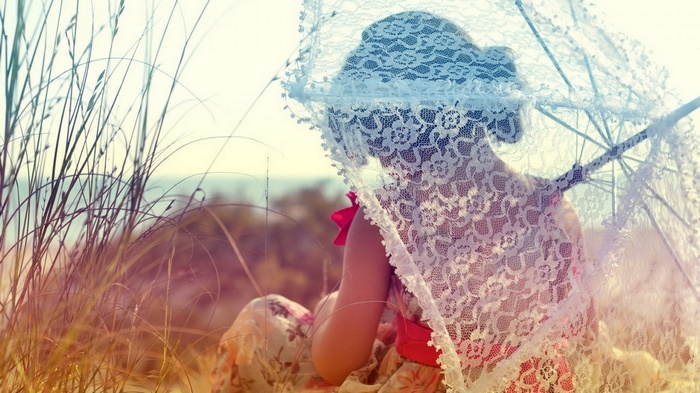 Girl with lace parasol in tall grass