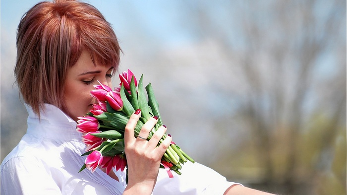 Woman smelling a bouquet of pink tulips
