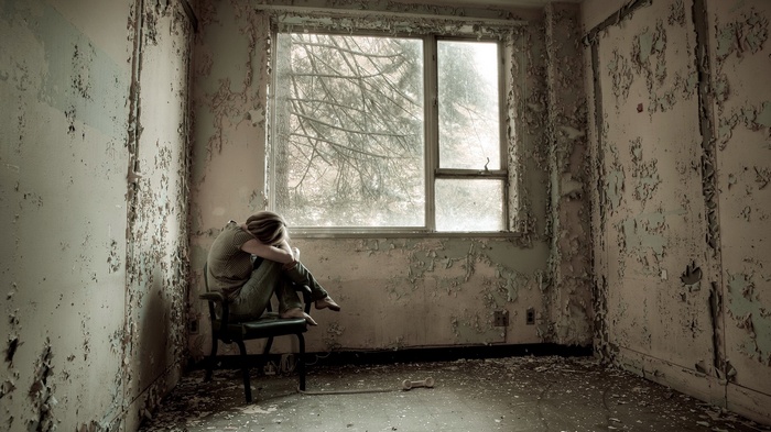 Person sitting in abandoned room by window