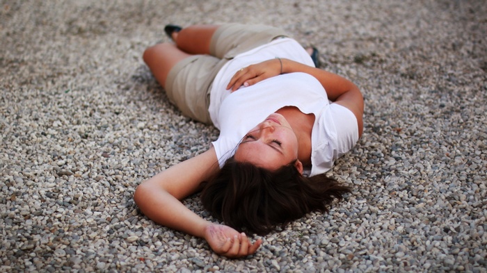 Woman lying on gravel ground