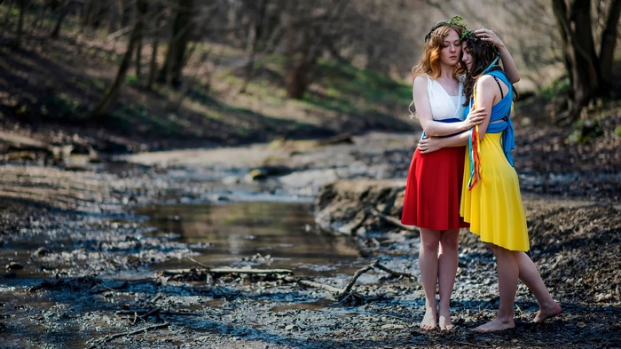 Two women embracing in a forest by a stream