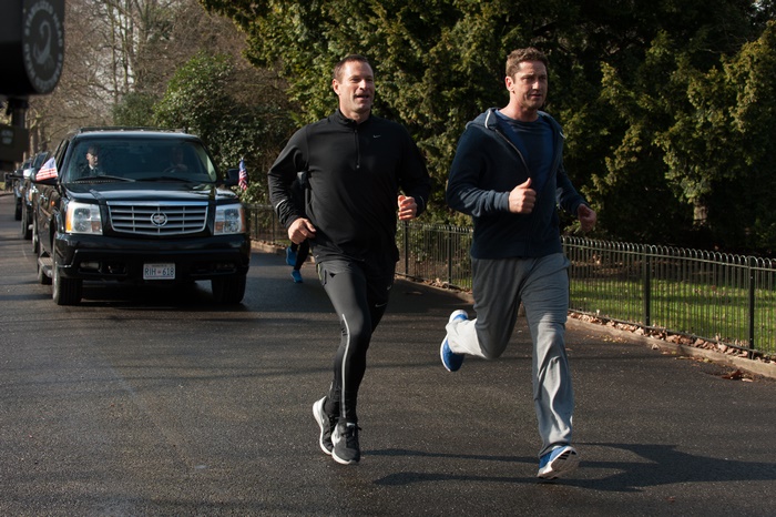 Gerard Butler running with a man next to a motorcade