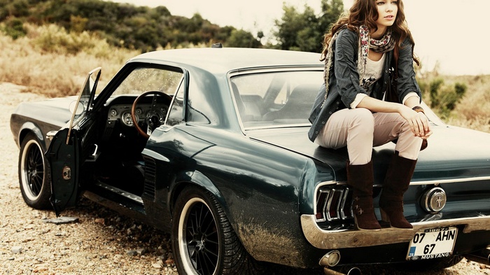 Woman sitting on a vintage Ford Mustang