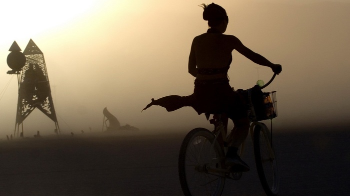 Woman on bicycle in dusty desert landscape