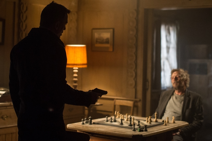 Daniel Craig holding a gun in front of a chessboard