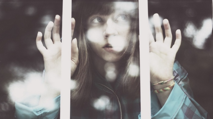 Girl looking through a window with hands pressed against it
