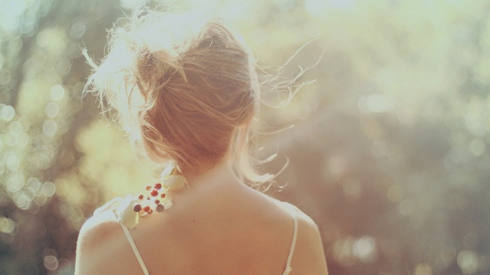 Woman with flowers on her shoulder in sunlight