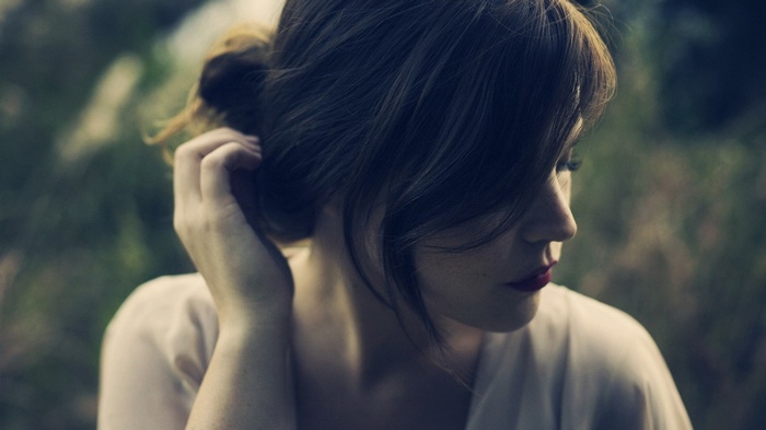 Woman with dark hair touching her head