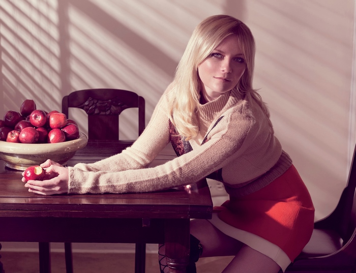 Kirsten Dunst sitting at a table with apples