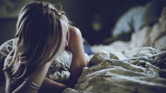 Woman lying in bed with blanket