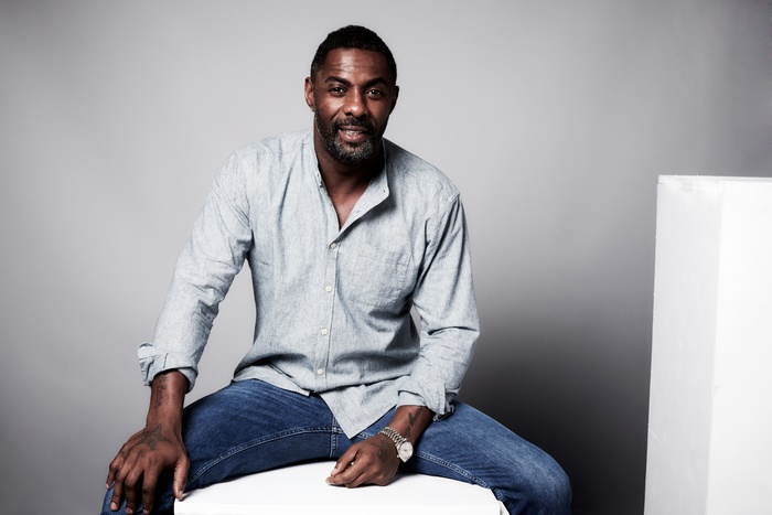 Idris Elba sitting on a white cube