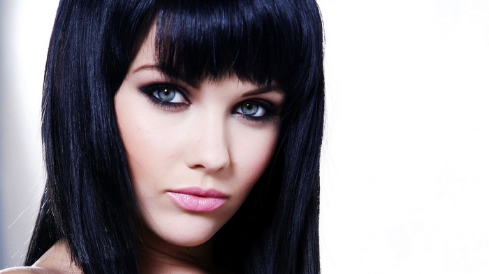 Close-up of a woman with black hair and blue eyes