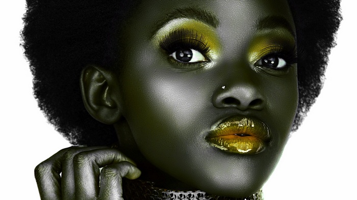 Woman with dark skin and gold makeup