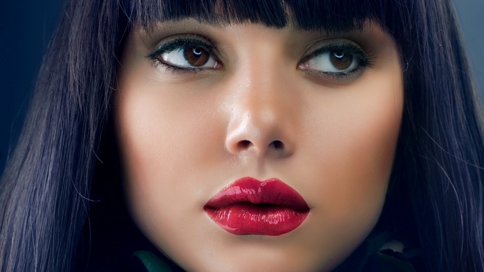 Close-up of a woman's face with dark hair and red lipstick