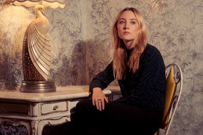 Saoirse Ronan sitting by a desk with a lamp