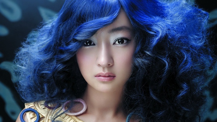 Woman with blue curly hair and makeup
