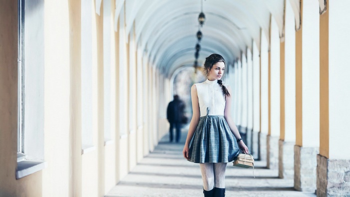 Woman in white top and skirt holding books in arcade