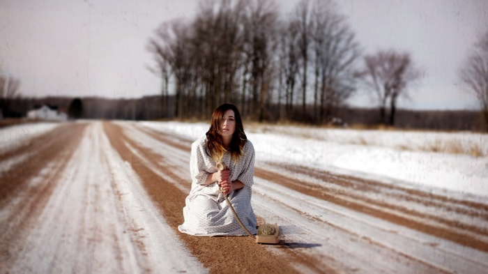 Woman with old telephone on snowy road