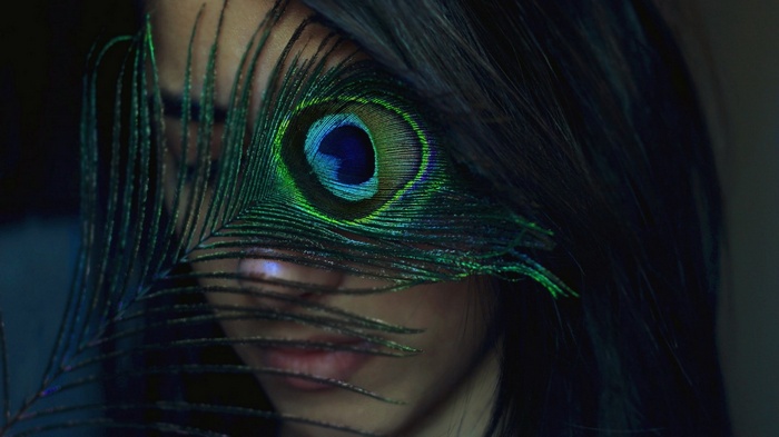 Woman with peacock feather over face
