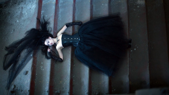 Woman in black dress lying on stairs