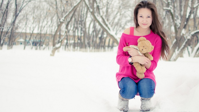 Woman holding a teddy bear in the snow