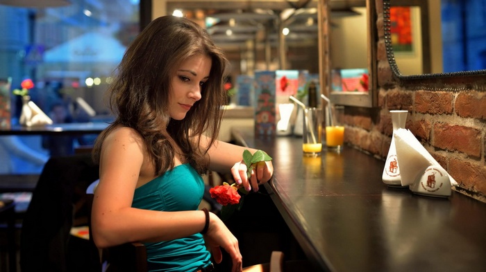 Woman holding a red rose at a bar
