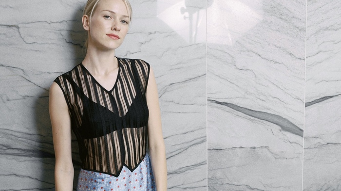 Naomi Watts posing against a marble wall