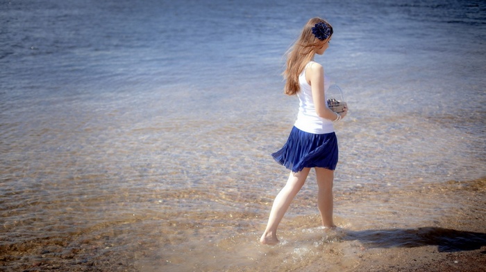 Girl walking on a beach with a basket