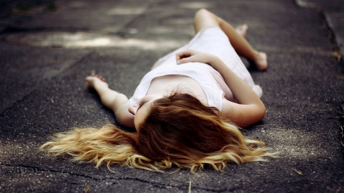 Woman lying on asphalt road