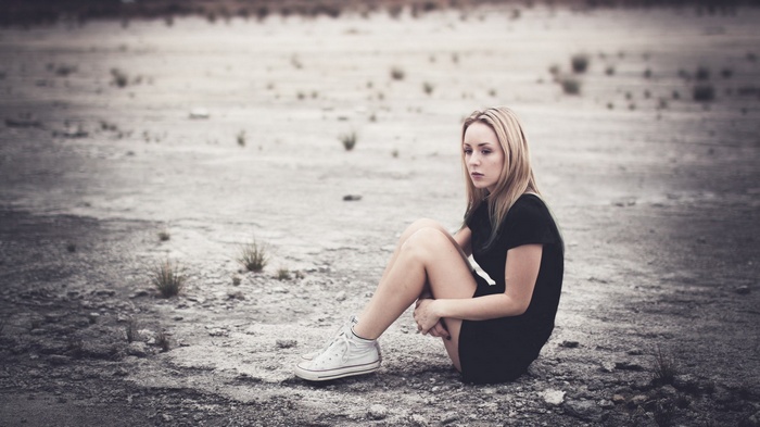 Woman sitting in a barren landscape