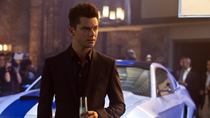 Dominic Cooper in a suit holding a drink