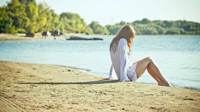 Woman in white shirt sitting on a beach