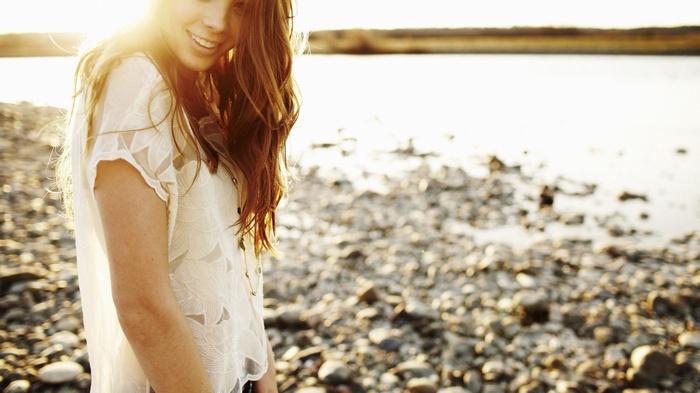 Woman smiling on a rocky beach at sunset