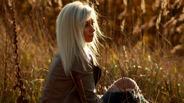 Woman with blonde hair sitting in tall grass