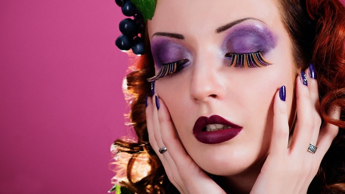 Woman with dramatic purple makeup and grapes