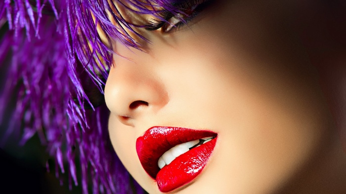 Close-up of a woman's face with purple hair and red lips