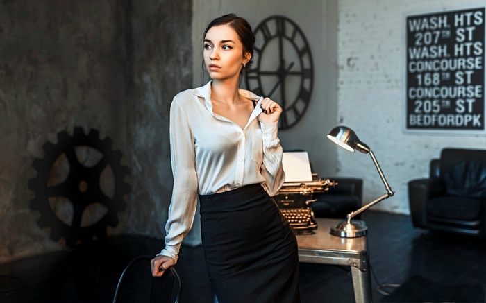 Woman in office with vintage typewriter and desk lamp