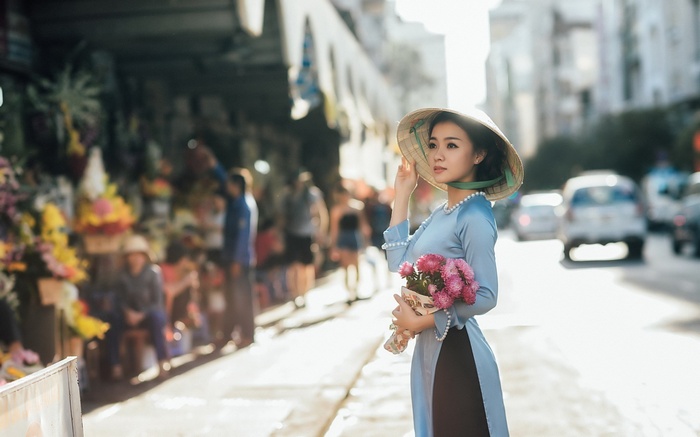 Woman in traditional Vietnamese dress holding flowers