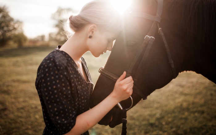 Woman and horse in a field at sunset