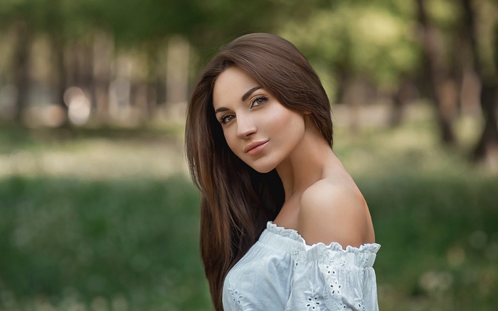 Woman with long brown hair in a white off-the-shoulder top